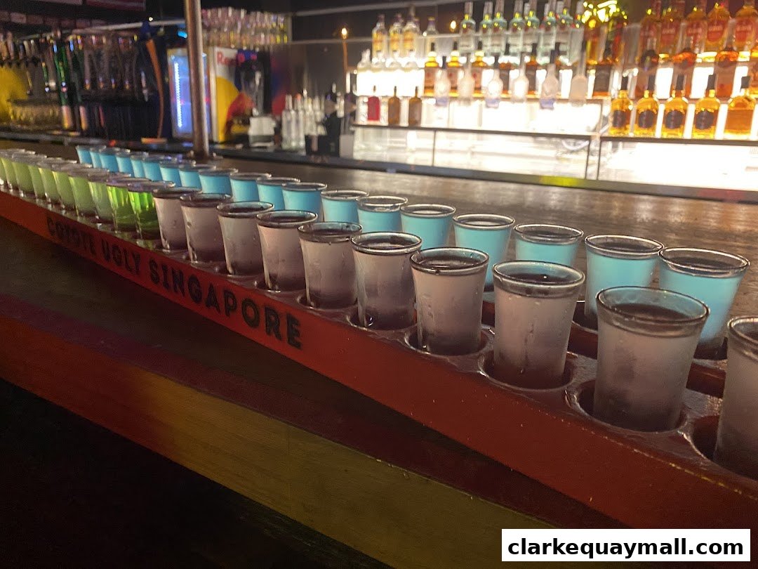A row of colorful shots lined up on a bar at Coyote Ugly Saloon Singapore.
