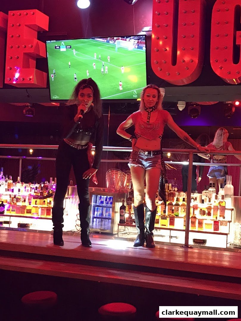 Two women perform on stage at Coyote Ugly Saloon with a soccer game playing on a screen.