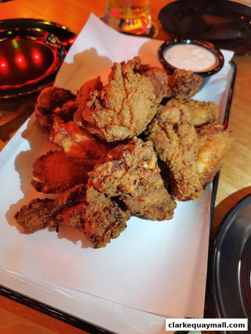 A platter of crispy fried chicken pieces served with a side of dipping sauce.