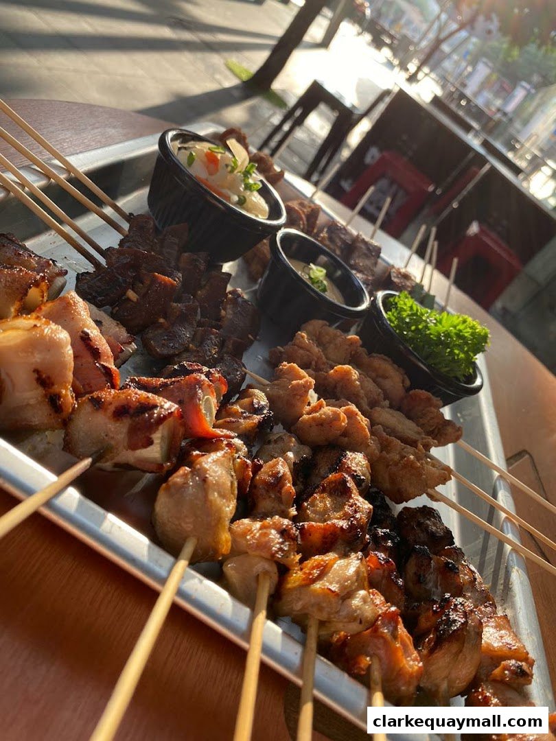 A platter of assorted grilled meat skewers with dipping sauces and garnish.