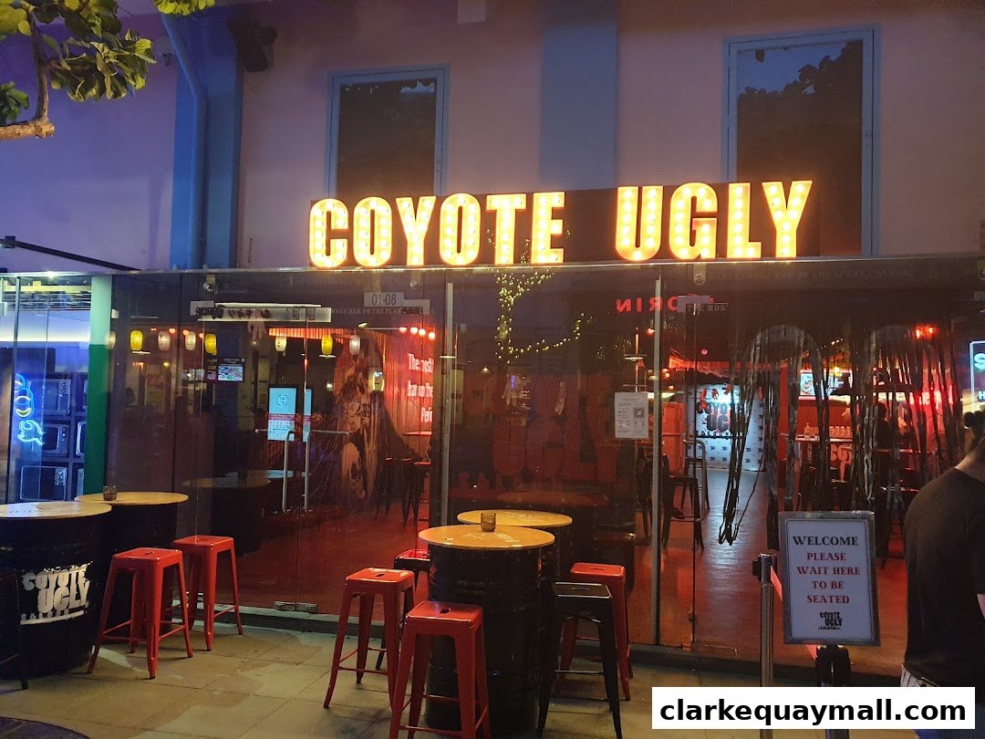 The exterior of Coyote Ugly Saloon Singapore with its iconic illuminated sign and seating area.