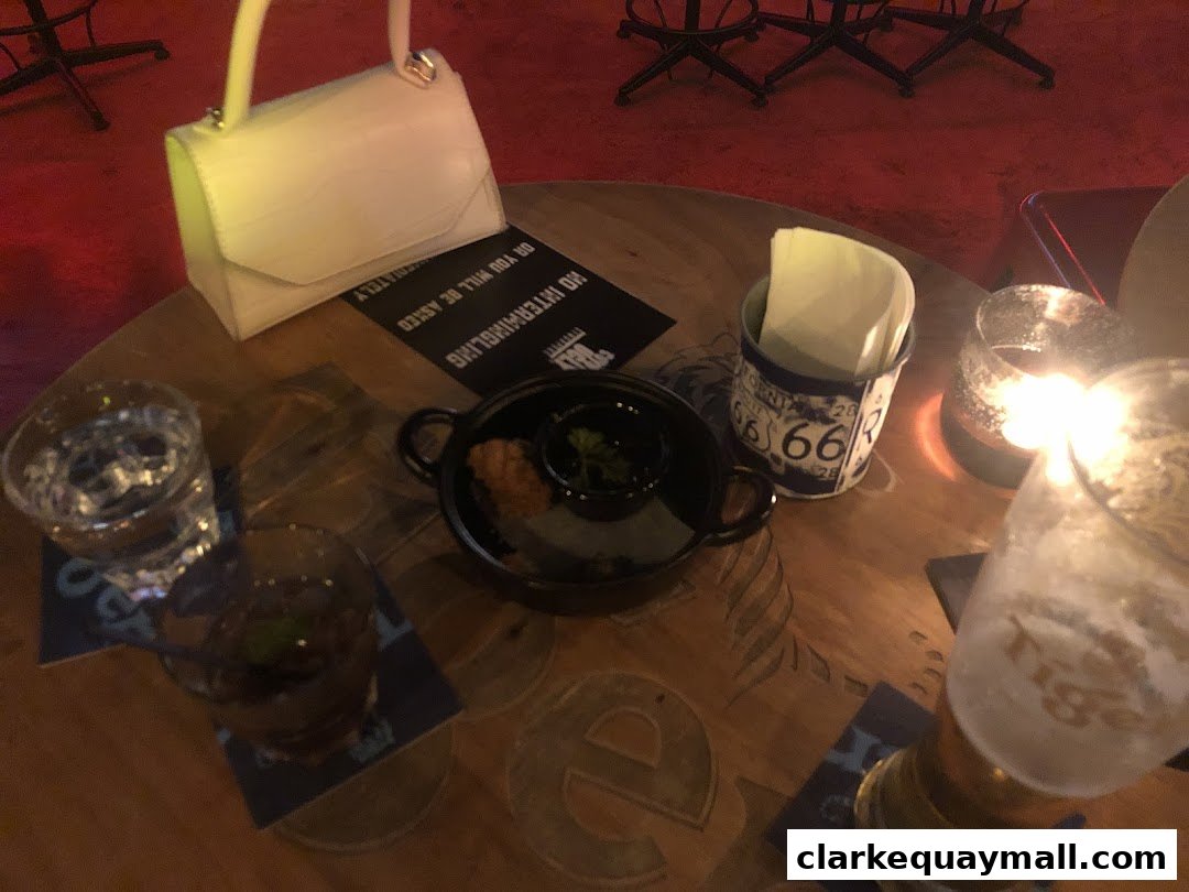A table at Coyote Ugly Saloon with drinks, a small dish, and a handbag.