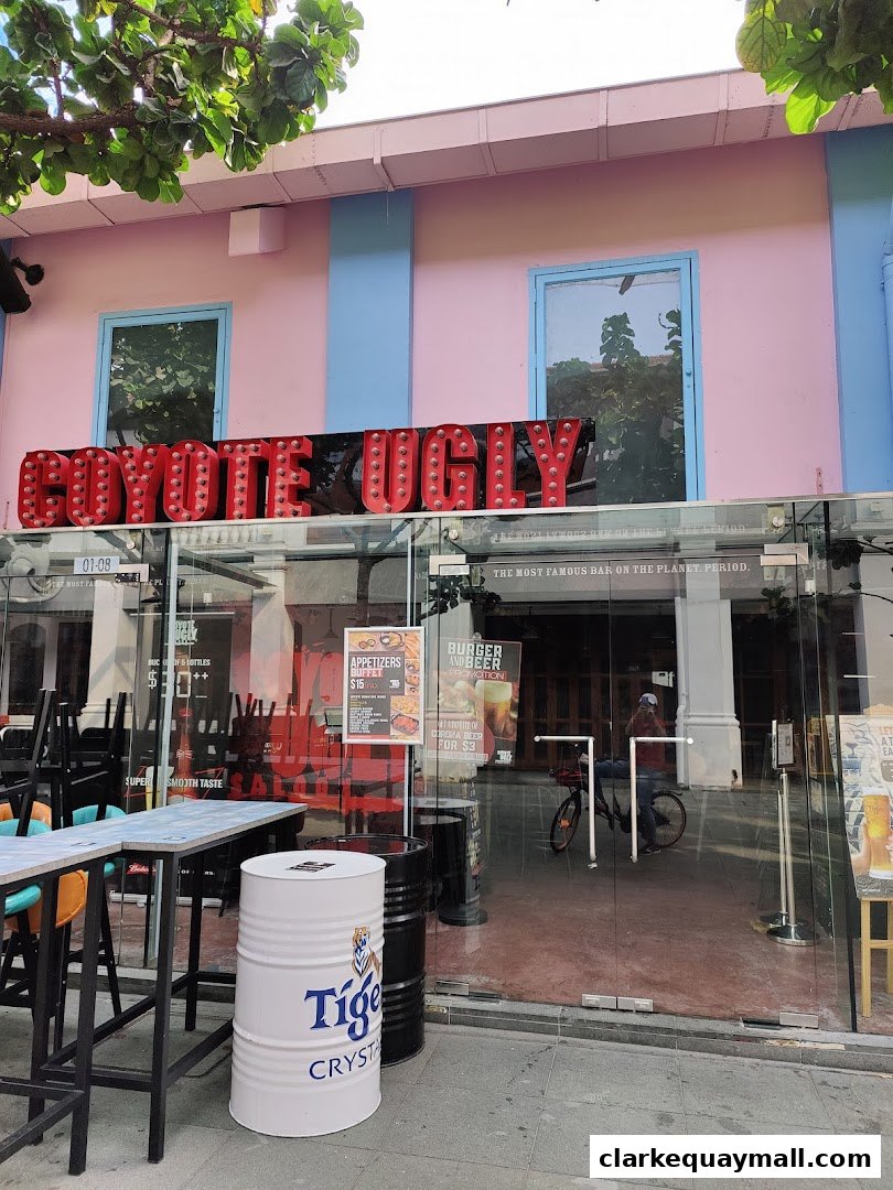 The exterior of Coyote Ugly Saloon Singapore with its iconic sign and glass doors.
