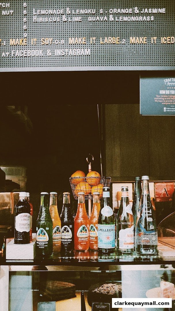 A display of bottled drinks and oranges at a coffee shop counter.