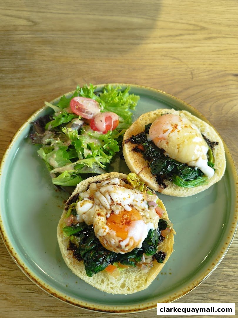 Two open-faced sandwiches with poached eggs and spinach, served with a side salad.