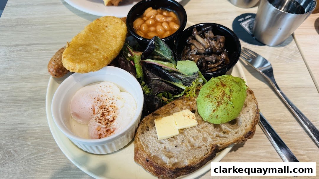 A hearty breakfast plate with poached eggs, avocado toast, hash brown, sausage, beans, and mushrooms.