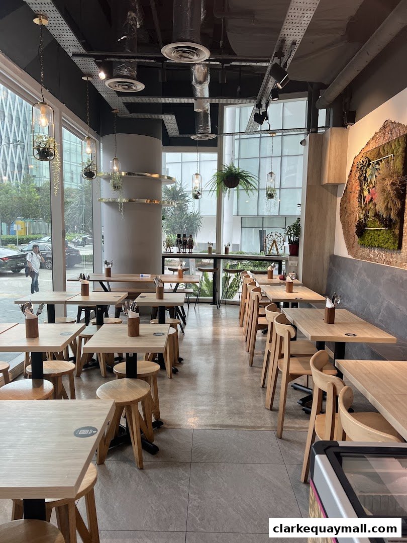 Interior of a modern coffee shop with wooden tables, chairs, and hanging plants.