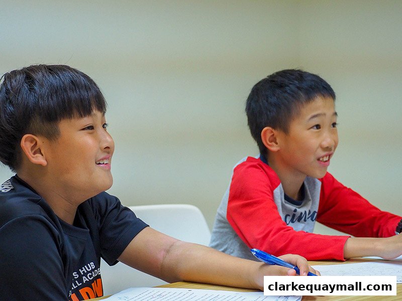 Two young boys are attentively listening and participating in a class at CreativEdge Learning.
