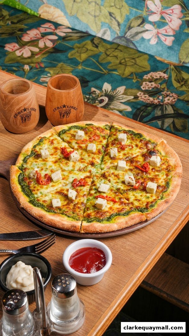 A delicious pizza with cheese, pesto, and sun-dried tomatoes, served with dipping sauces.