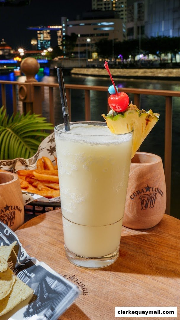 A refreshing cocktail with pineapple and cherry garnish, served with fries and chips.