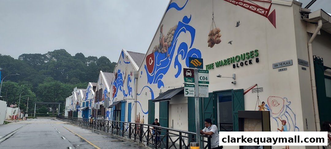 A row of warehouses with vibrant murals depicting maritime scenes and people.