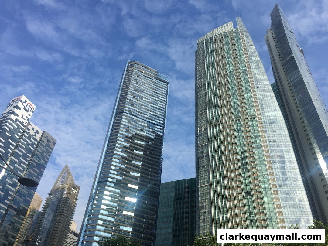A view of modern skyscrapers against a blue sky with scattered clouds.