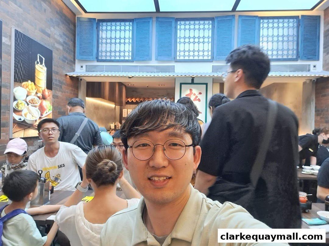 A group of people are dining at tables inside a restaurant with decorative blue shutters on the wall.