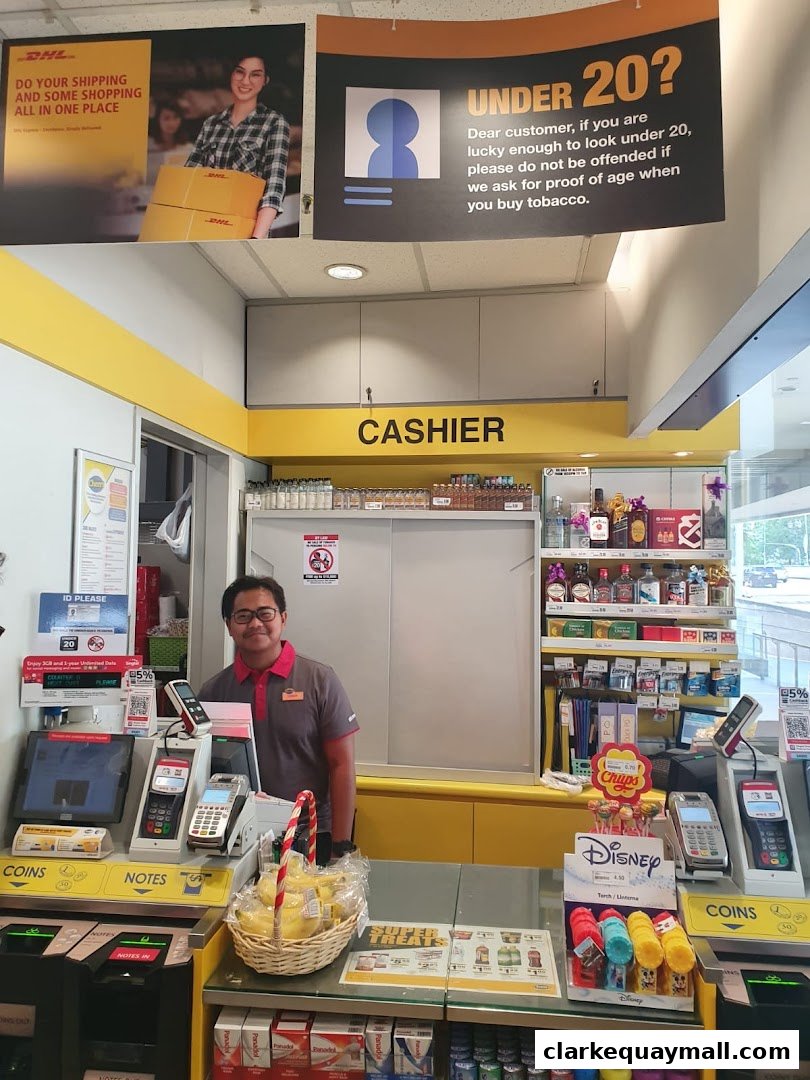 A cashier stands behind a counter at a DHL Express Service Point, with various products and signage visible.