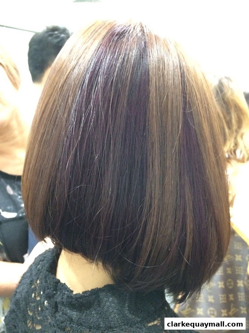 A close-up of a bob haircut with subtle purple highlights and a black lace top.
