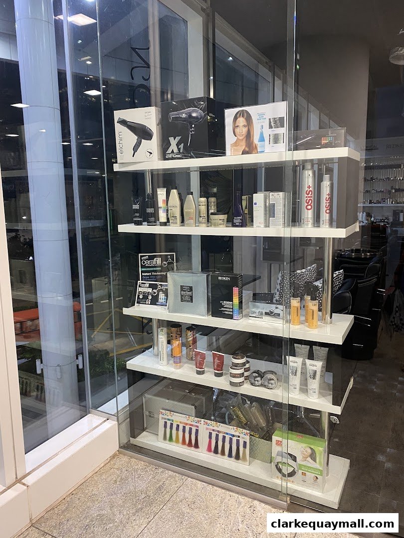 A salon window display featuring hair dryers, styling products, and hair color swatches.