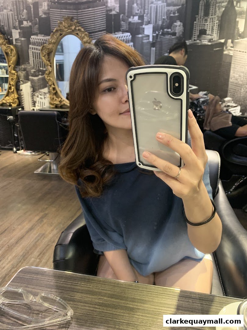 A woman takes a selfie in a salon chair, showing off her styled hair.