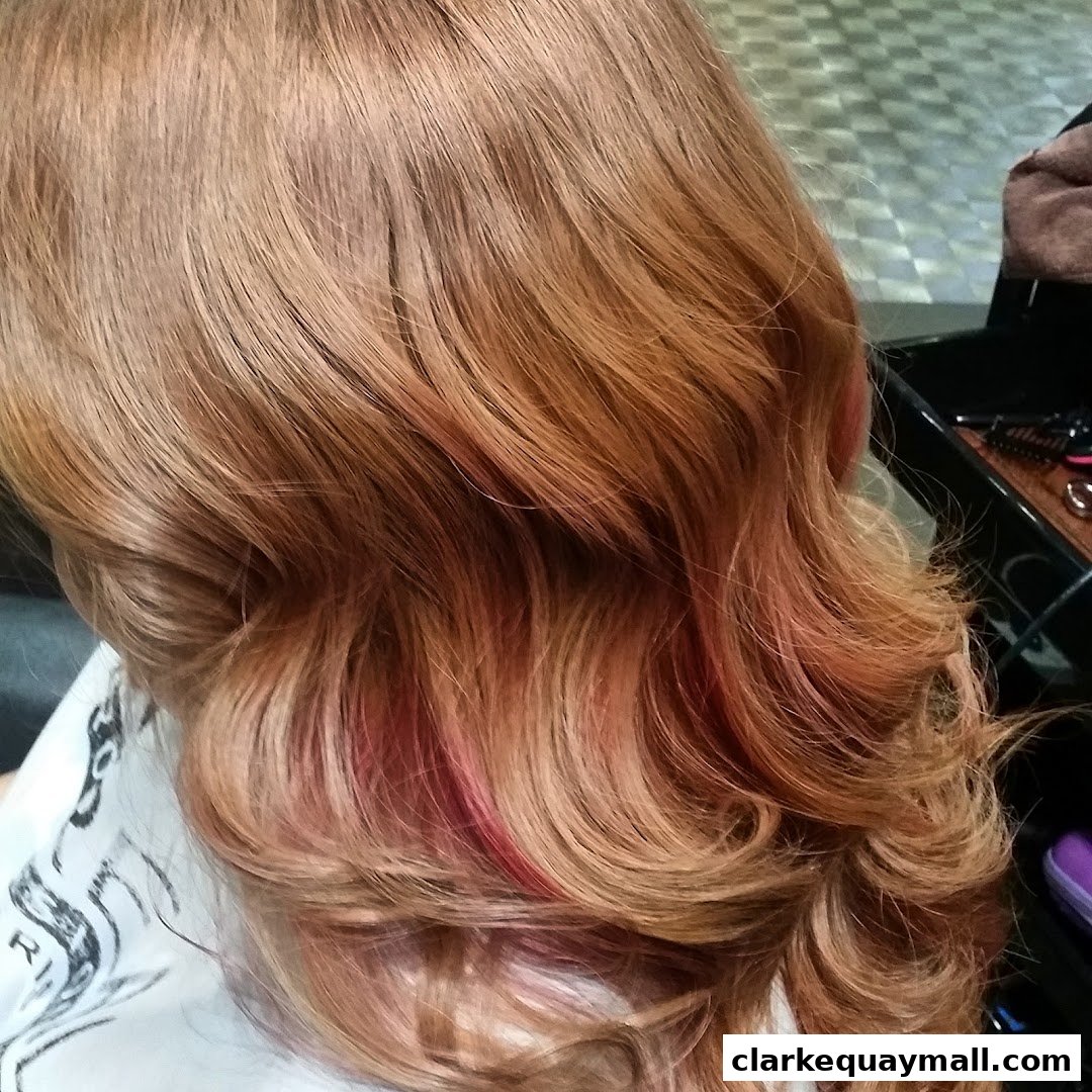 Close-up of a person's wavy, reddish-brown hair with subtle pink highlights.