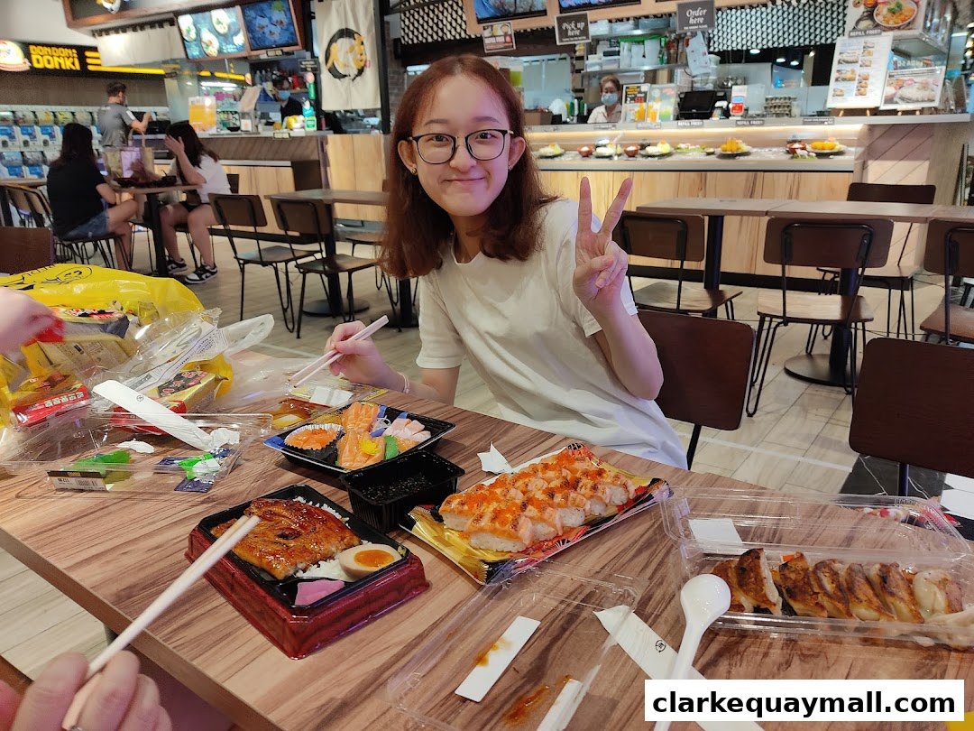 A young woman enjoys a meal of sushi and gyoza at DON DON DONKI.