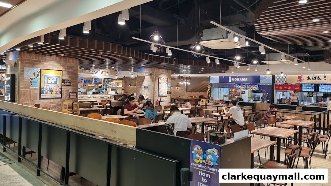 Interior view of a bustling food court with multiple Japanese food stalls and dining tables.
