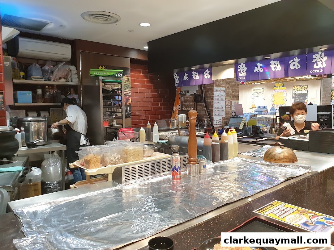 Chefs preparing food behind a counter with various ingredients and cooking equipment.
