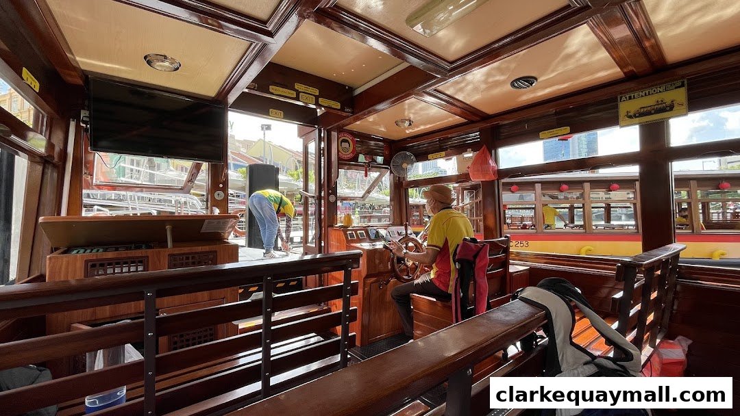 Interior view of a wooden boat with a captain at the helm and a crew member attending to duties.
