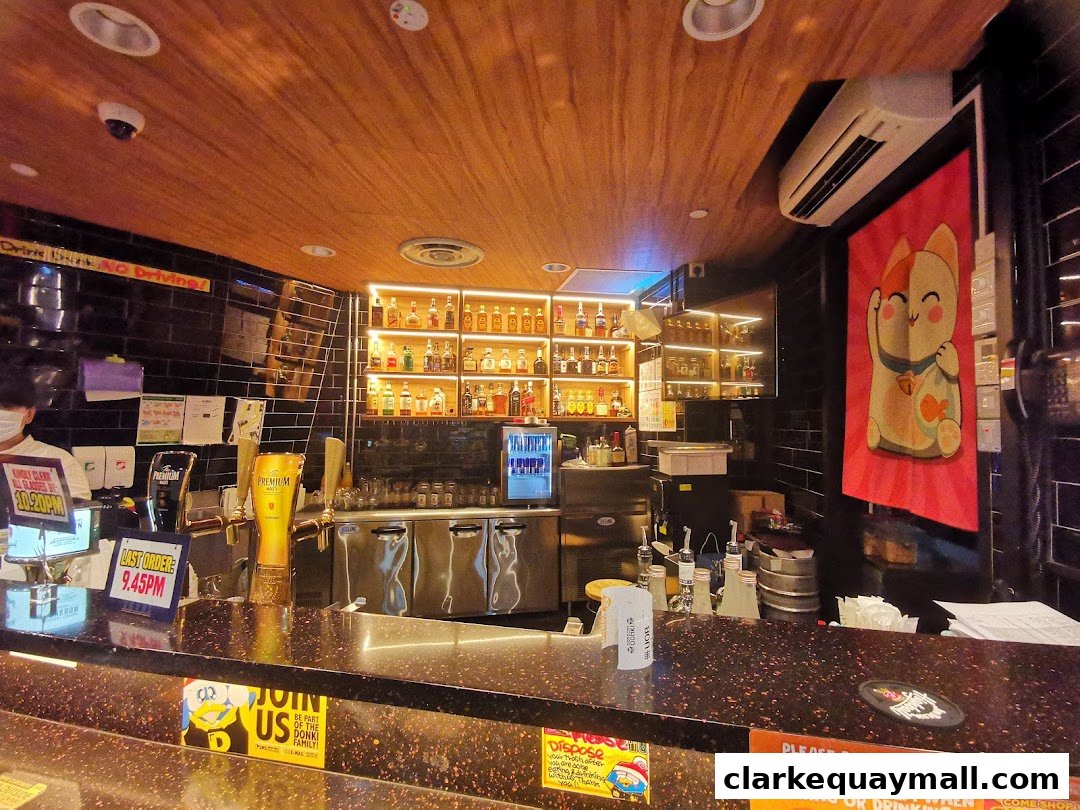 Interior of a bar with a well-stocked liquor shelf, beer taps, and a counter.