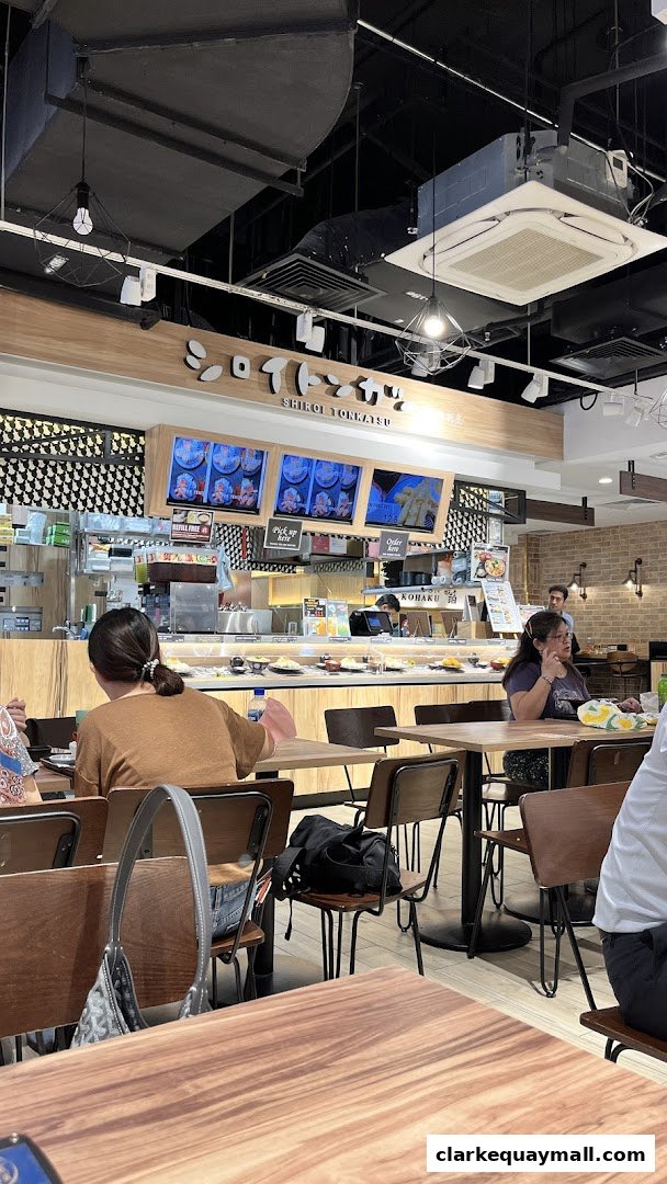 Interior view of a Japanese restaurant with a conveyor belt sushi bar and dining tables.