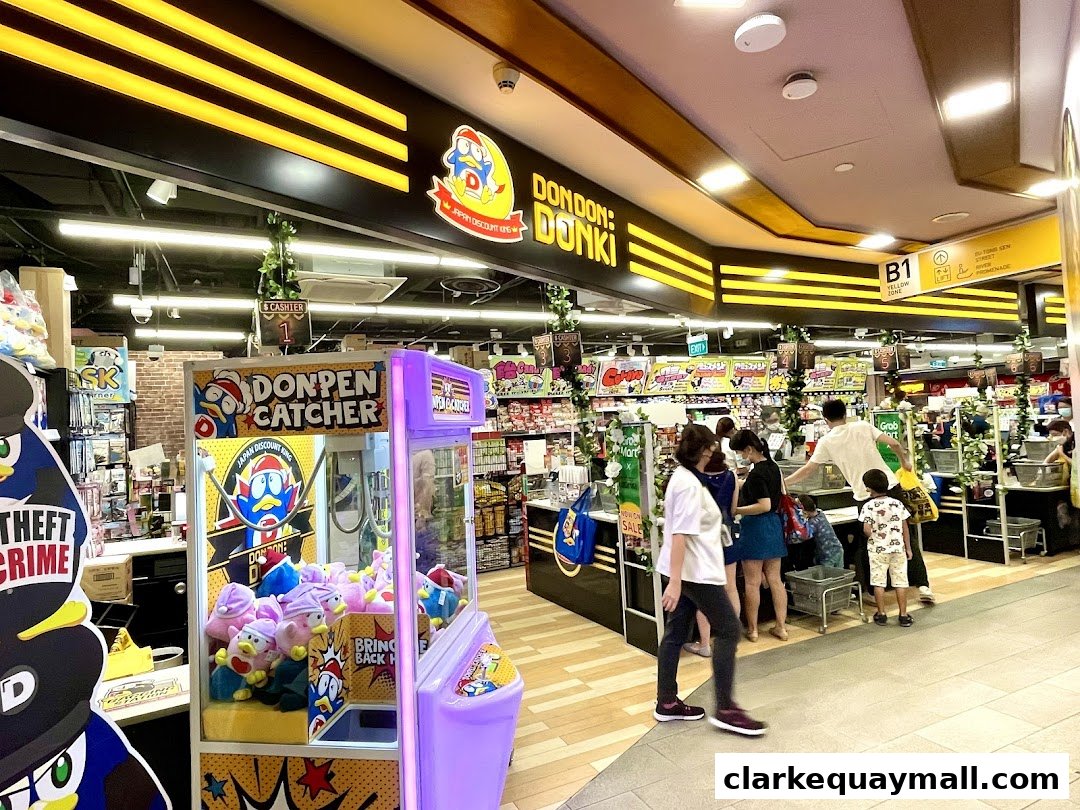 Interior view of a DON DON DONKI store with shoppers and a claw machine.