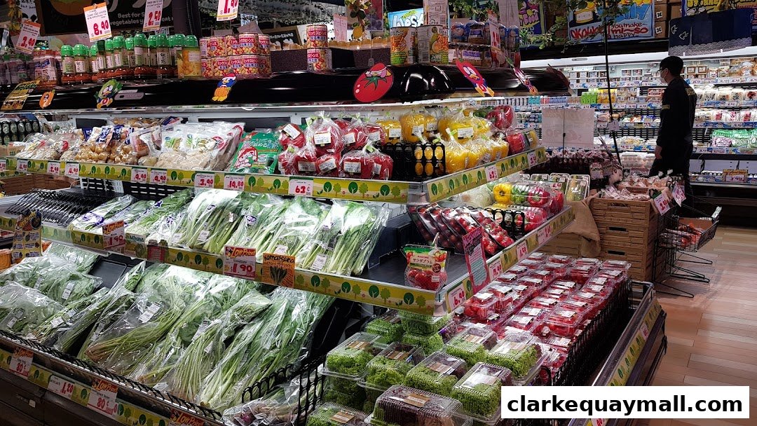 A wide selection of fresh produce, including leafy greens, peppers, and tomatoes, displayed on shelves in a supermarket.