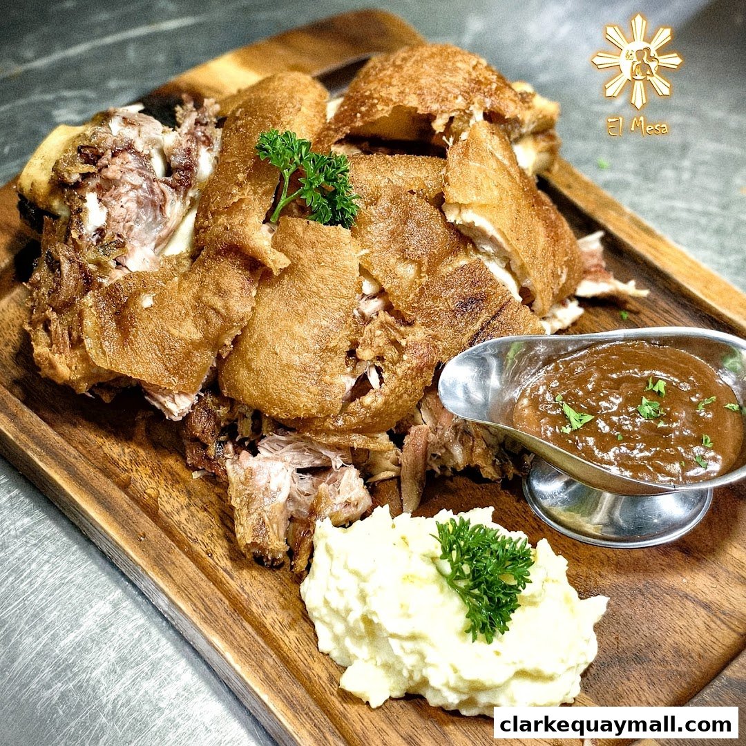 A crispy Filipino pork knuckle dish served with mashed potatoes and gravy.