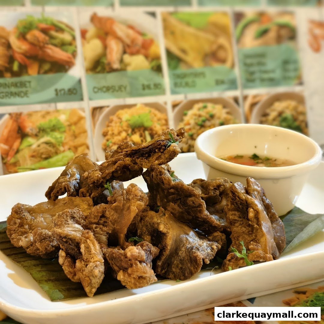 A plate of crispy fried seafood with a dipping sauce, with a blurred menu in the background.