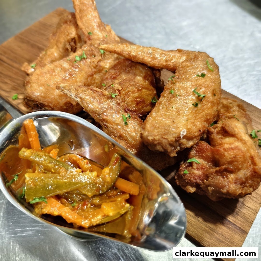 Crispy fried chicken wings served with a side of pickled vegetables on a wooden board.