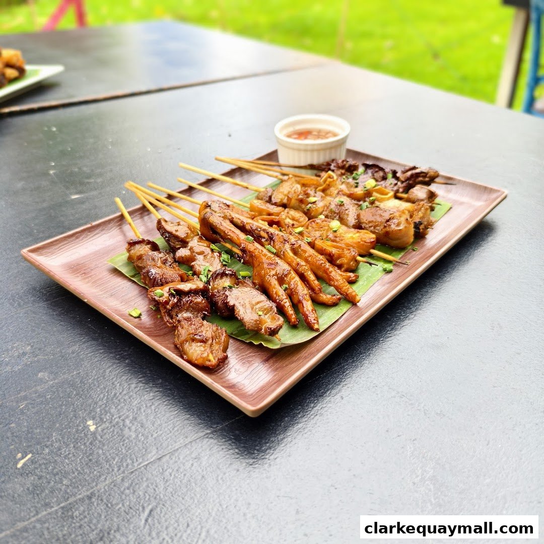 A platter of assorted grilled Filipino skewers with a side of dipping sauce.