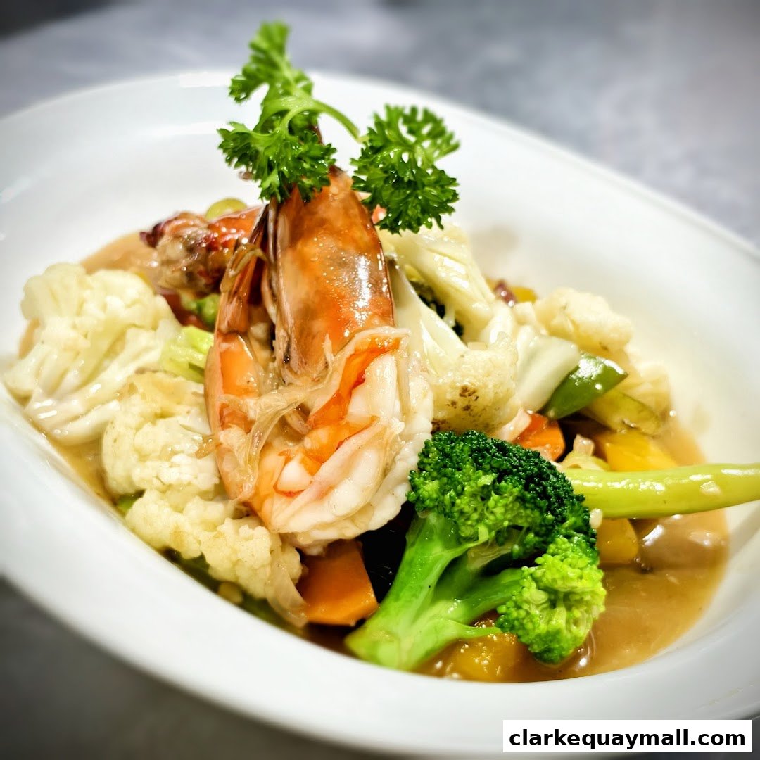 A close-up of a seafood dish with shrimp, broccoli, cauliflower, and carrots in a savory sauce.