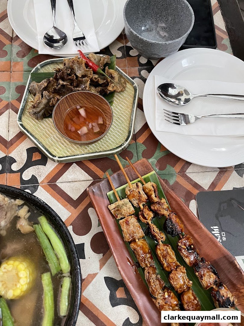 A table setting with Filipino seafood dishes, including crispy appetizers and grilled skewers.