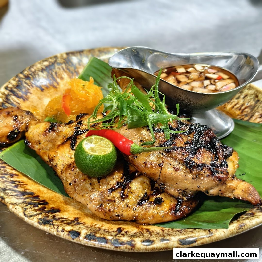 A plate of grilled chicken with a side of dipping sauce, lime, and chili.