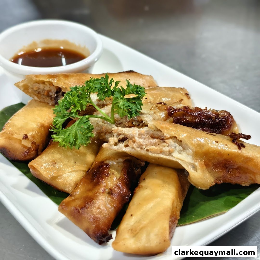 Crispy Filipino spring rolls served with a dipping sauce and garnished with parsley.