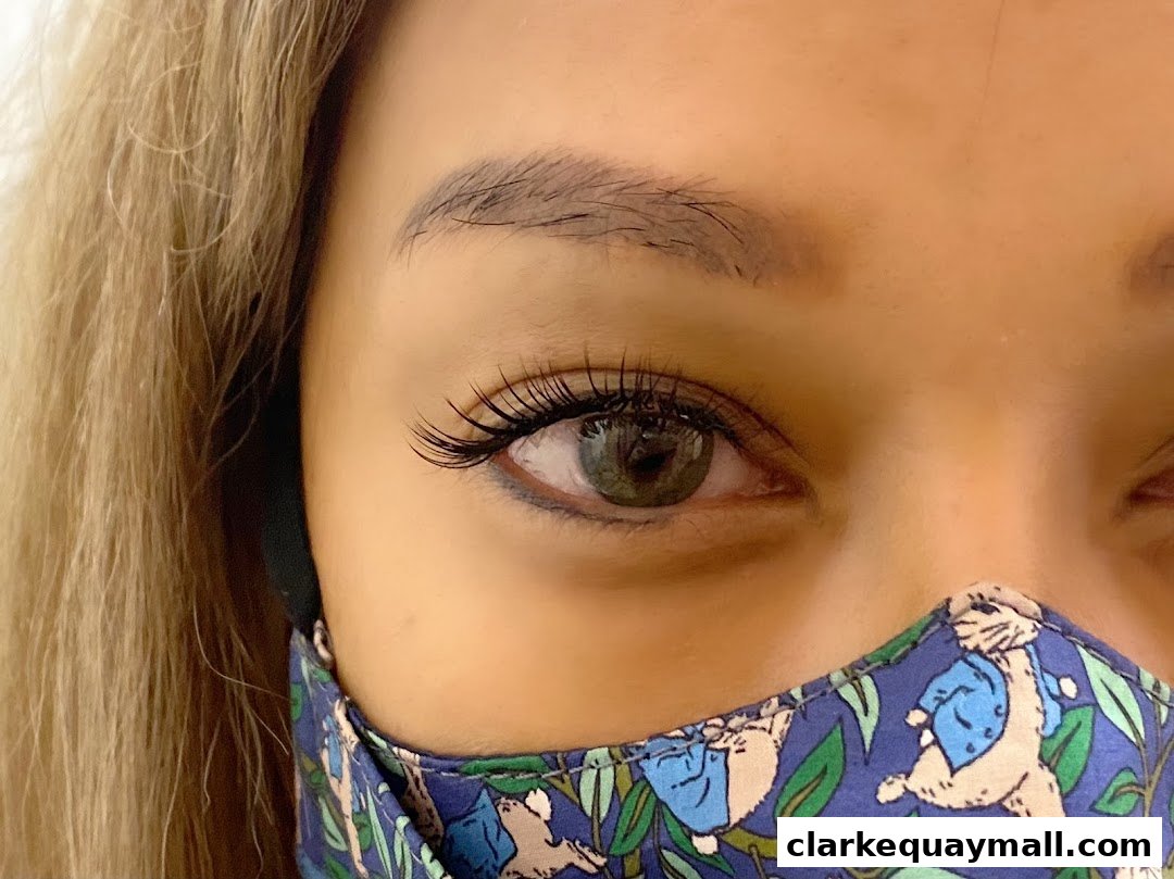 Close-up of a woman's eye with long lashes and a patterned face mask.