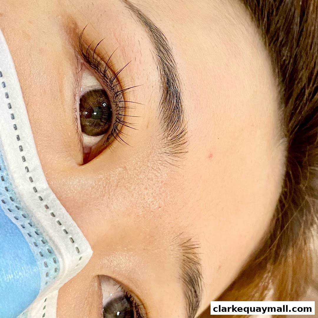Close-up of a person's eye with perfectly curled lashes and a medical mask.