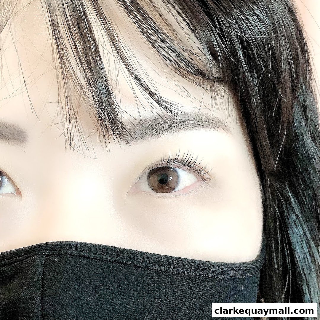 Close-up of a person's eyes with long lashes and a black face mask.