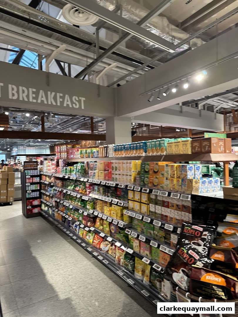 A wide aisle in a supermarket with shelves stocked with various food and beverage products.