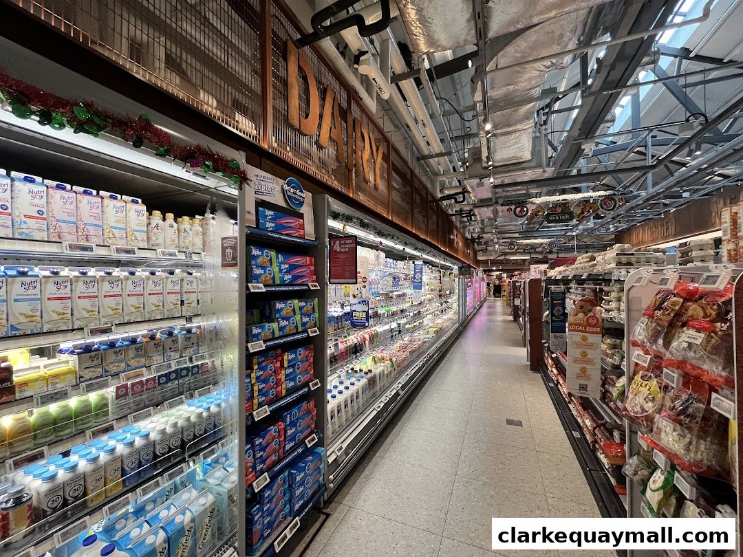 A wide aisle in a supermarket featuring dairy products and other groceries.
