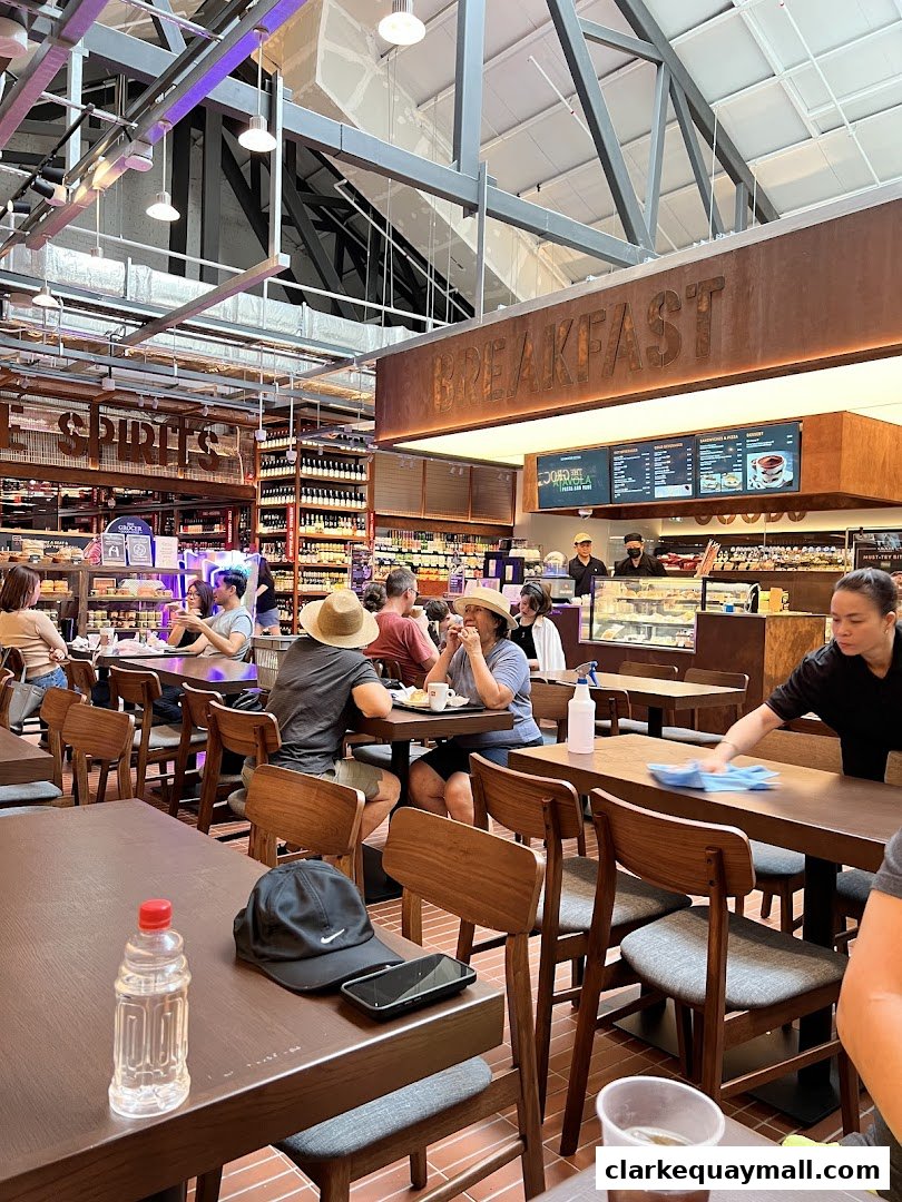 People dining at tables inside a well-lit grocery store with a 'Breakfast' sign.