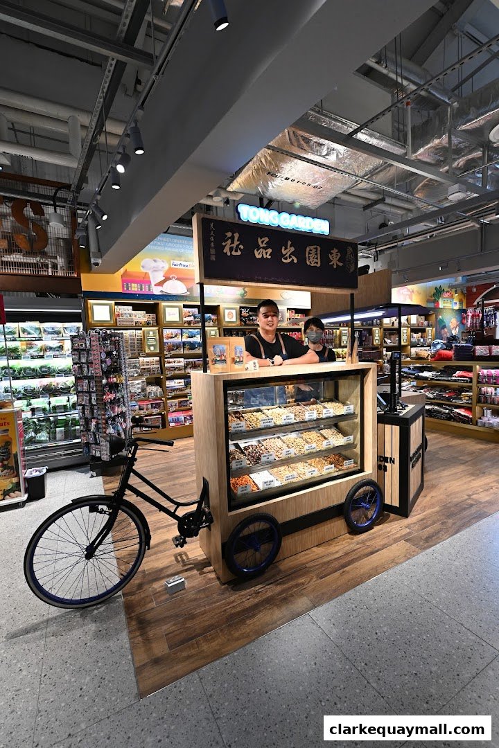 A display cart with various nuts and two staff members at FairPrice Finest Clarke Quay.