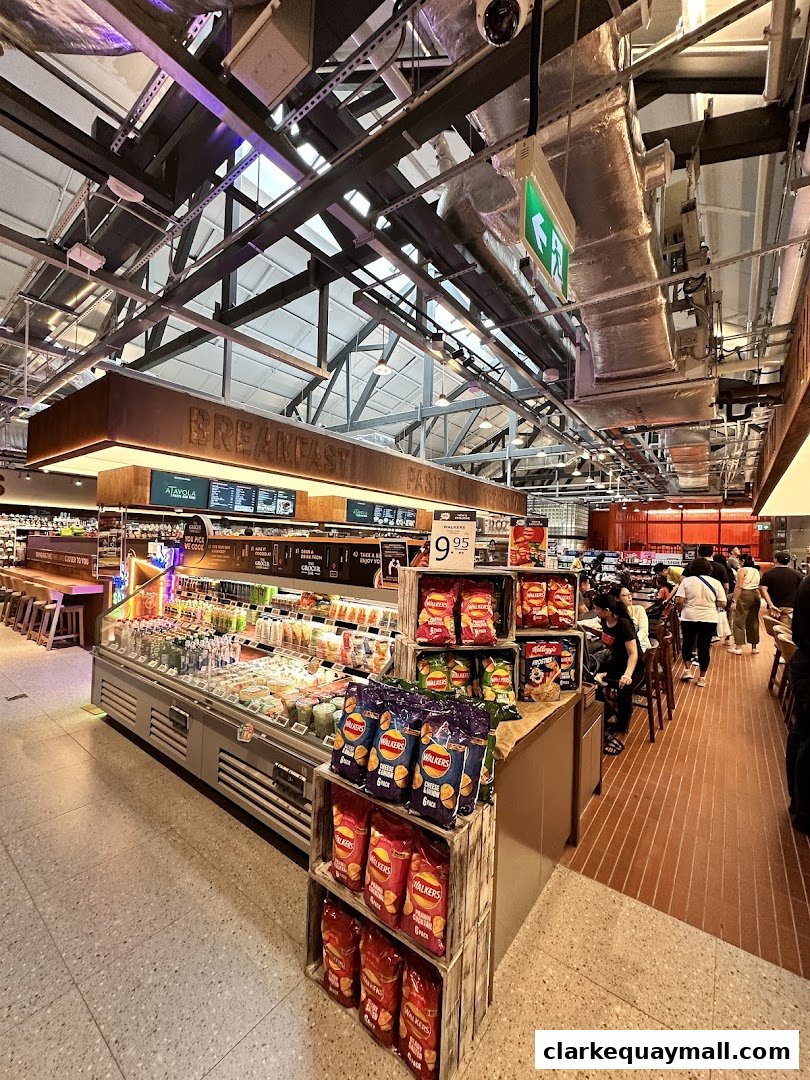 Interior view of a well-stocked supermarket with a focus on fresh produce and snacks.