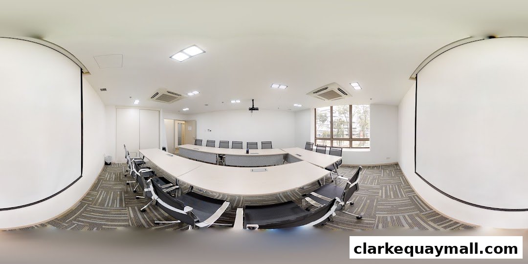 A modern conference room with a U-shaped table, chairs, projector, and screens.