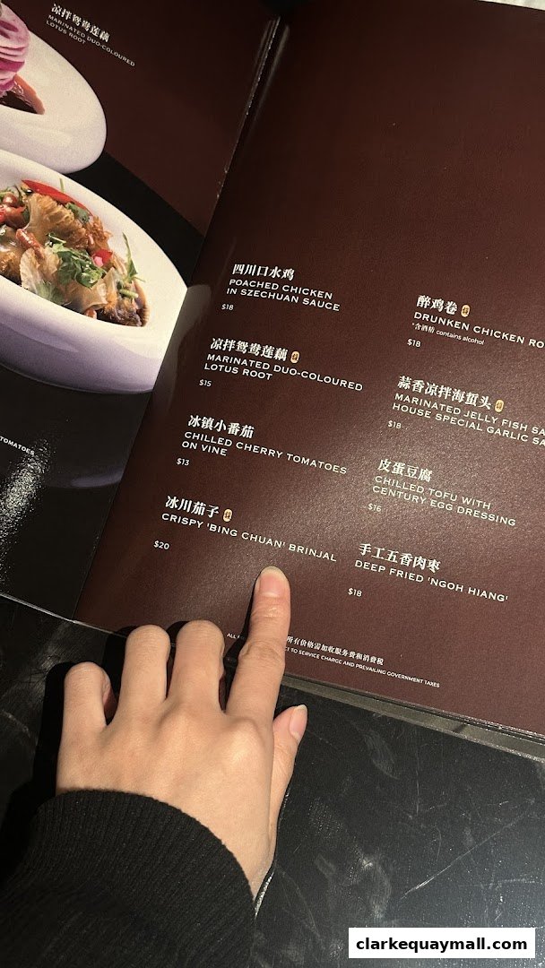 A person's hand pointing at a menu with various Teochew dishes and prices.