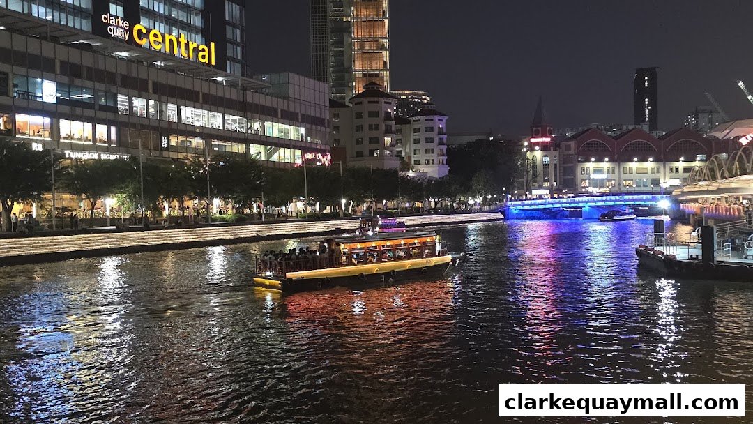 A lively night scene at Clarke Quay with a boat full of people on the river and illuminated buildings.