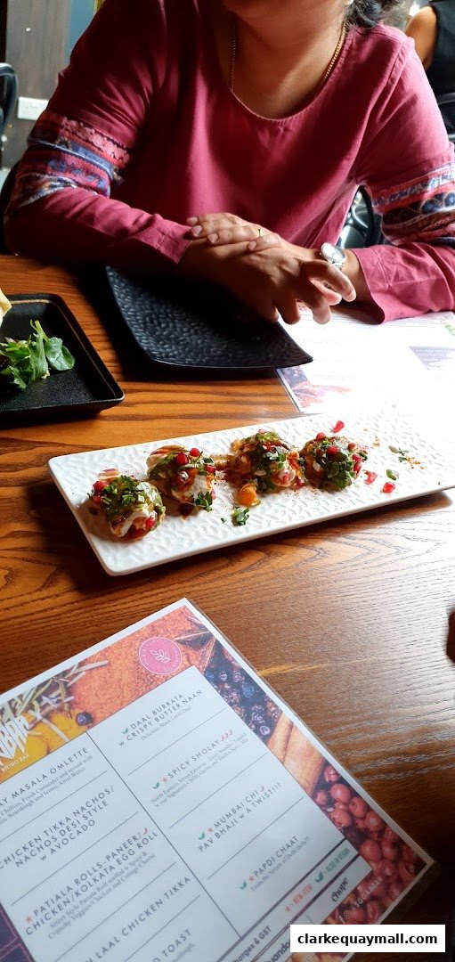 A person sits at a table with a plate of food and a menu.